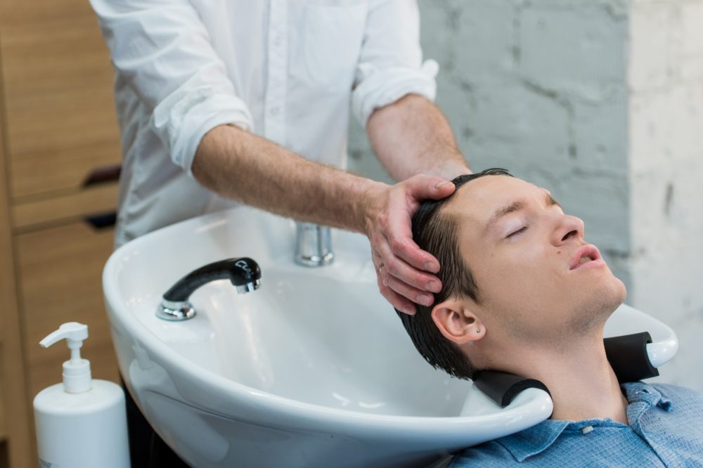 Young man at hairdresser salon getting his hair washed